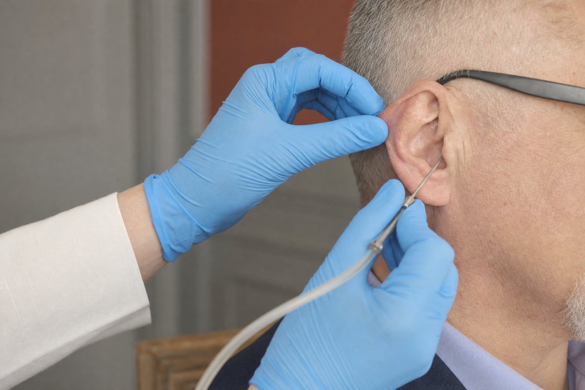 Gloved hands carrying out microsuction at the entrance of the ear canal
